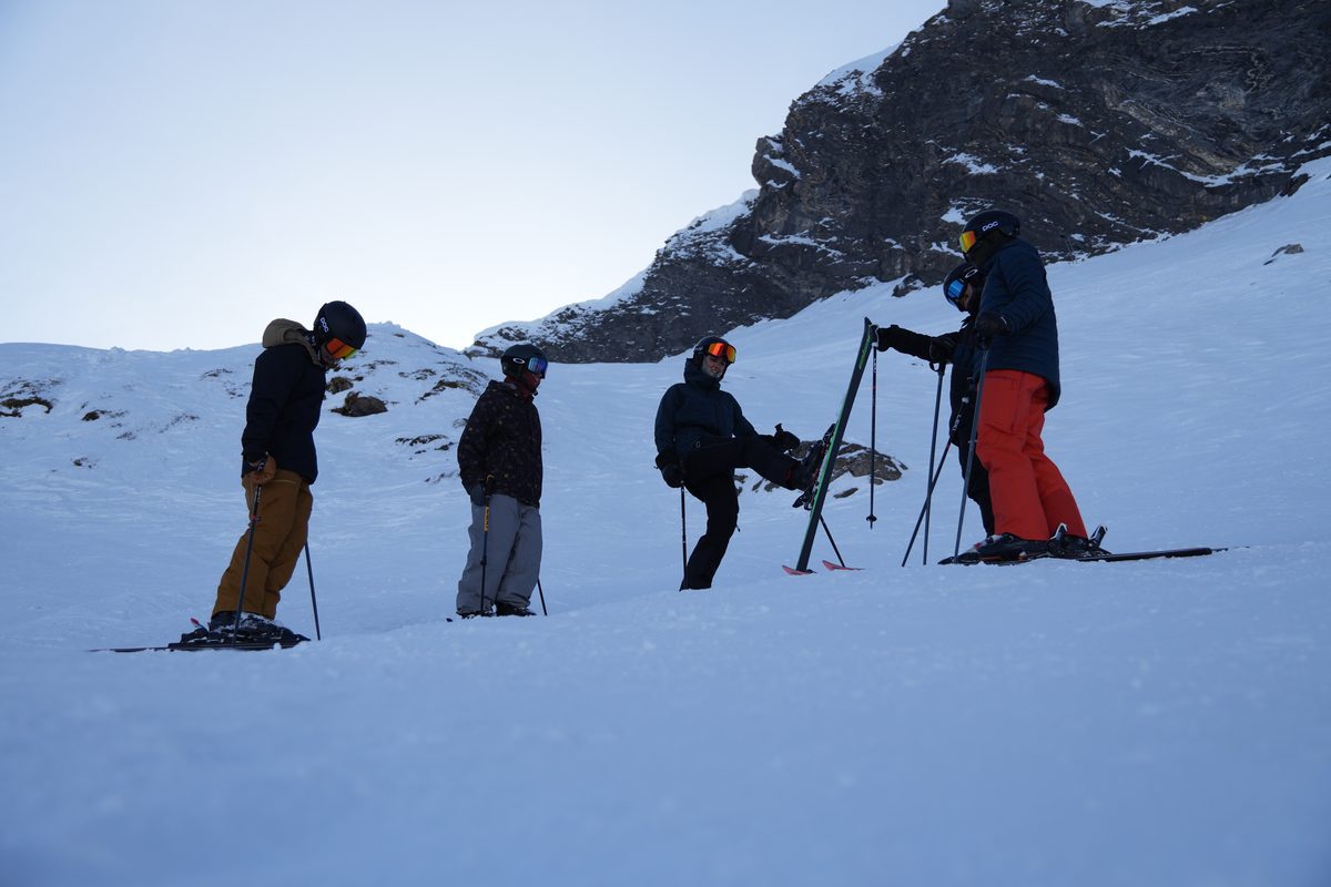 Students below a rocky alpine face in low evening light